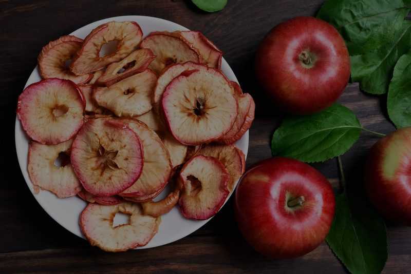 overhead close up shot of sliced cooked apples next to raw full apples