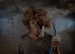 electrocuted man with curly smoking hair covered in smoke and dust holding a broken electrical cord