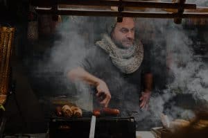 man in smokehouse cooking sausages on grill