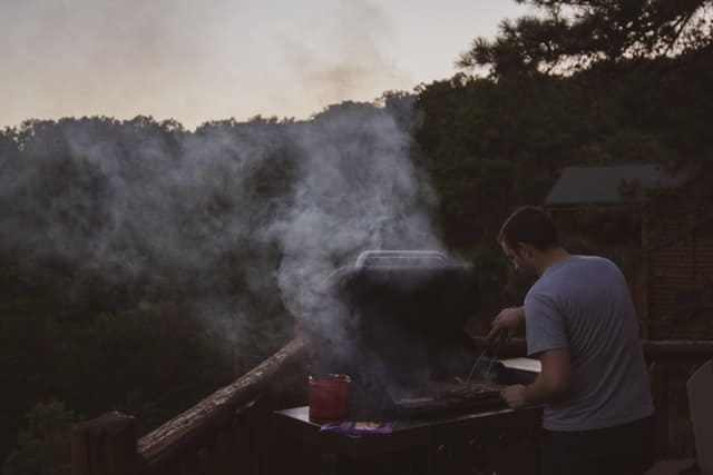 man using gas bbq to cook meat
